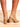 Model is wearing tan faux patent leather ankle boots with inner side zipper closure and 2" block heel