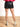 Model is wearing a black faux leather mini skirt with side slit.