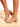 Model is wearing tan faux patent leather ankle boots with inner side zipper closure and 2" block heel