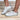 Model is wearing white/gold metallic star sneakers.