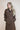 Woman wearing a brown trench coat against a plain background