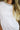 Woman wearing a white t-shirt with a decorative neckline against a brown background