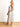 Model is wearing a cream linen midi dress with black piping.