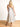 Model is wearing a cream linen midi dress with black piping.